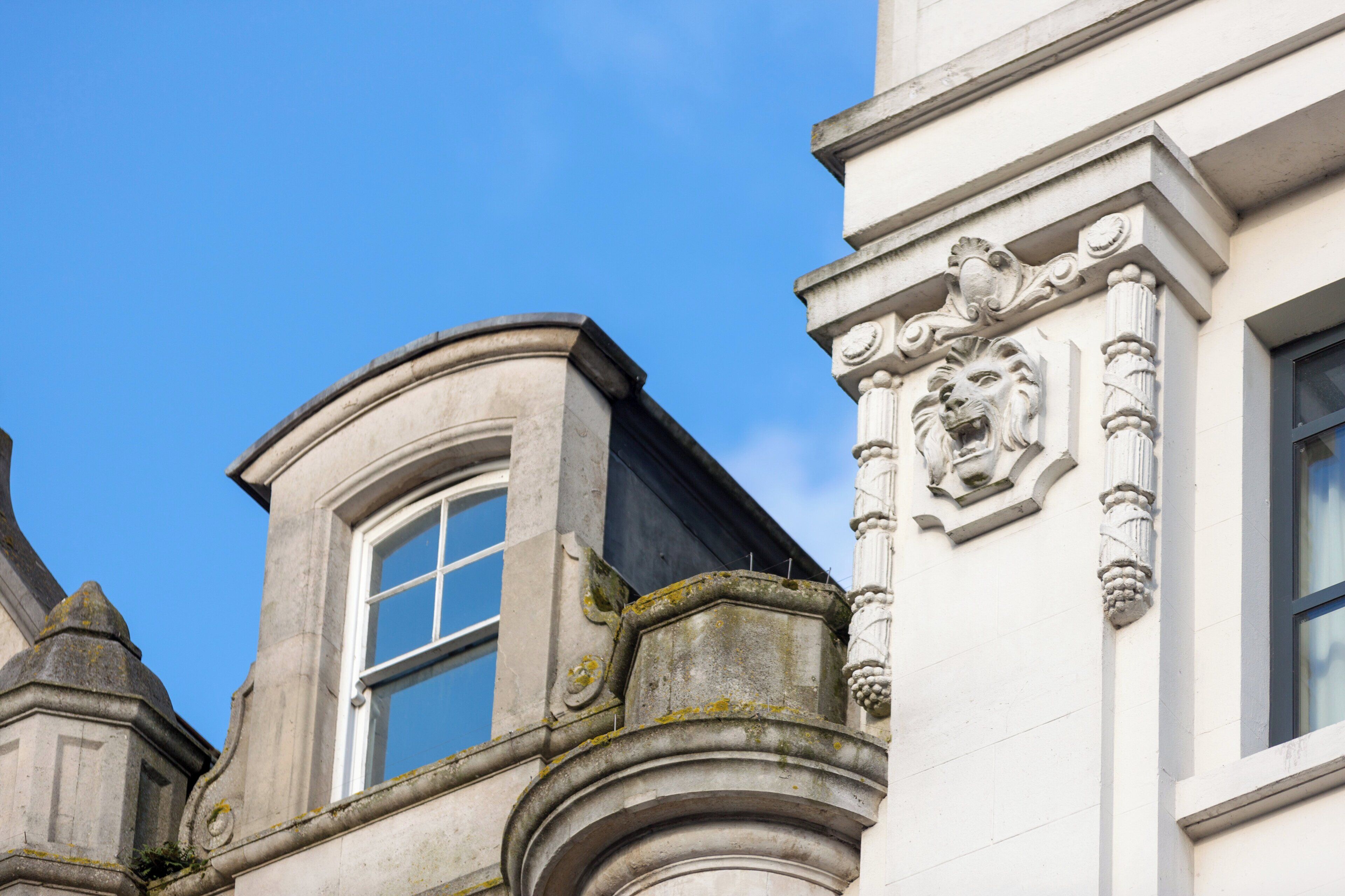 Esquina de un edificio con una ventana y detalles de piedra decorativa.