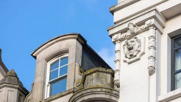 Esquina de un edificio con una ventana y detalles de piedra decorativa.