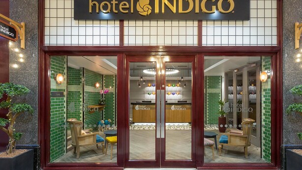The entrance of Hotel Indigo with a check-in counter, seating area, and potted plants. - Hotel Indigo Cardiff by IHG (Cardiff)