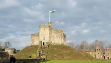 Un castillo histórico con asta de bandera, una colina cubierta de césped y cielo despejado.