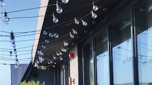 A modern building with a sloped roof, large windows, and outdoor seating with terracotta planters. - Hotel Indigo Cardiff by IHG (Cardiff)
