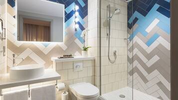Un baño moderno con un espejo grande, un lavabo, un inodoro y una ducha.