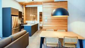 Una cocina moderna con horno empotrado, refrigerador y comedor con mesa y sillas.