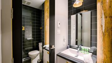 Un baño moderno con inodoro, lavamanos y espejo.
