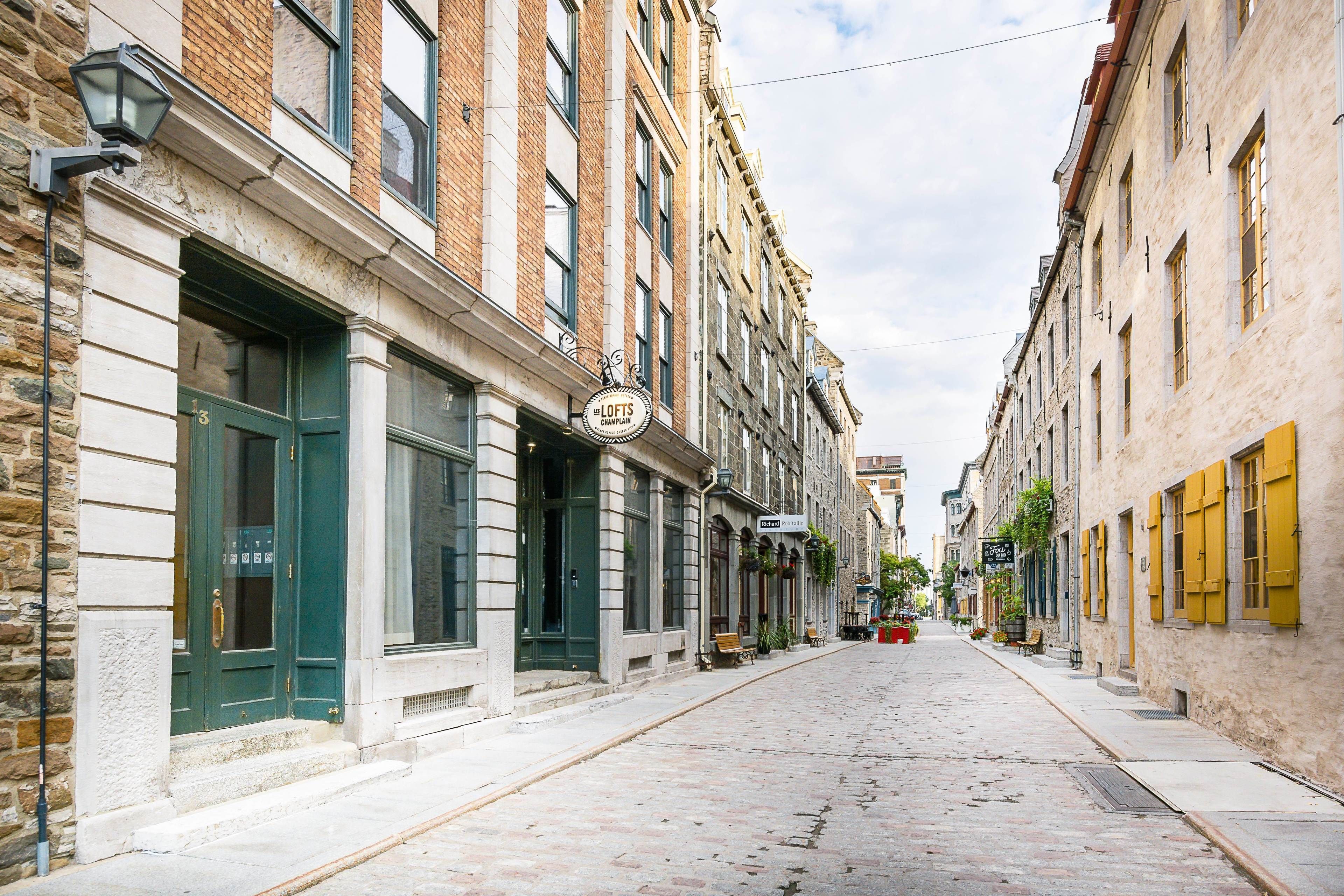 Una estrecha calle adoquinada flanqueada por edificios históricos, con un pub llamado "Lofts Champions" y varios otros comercios.