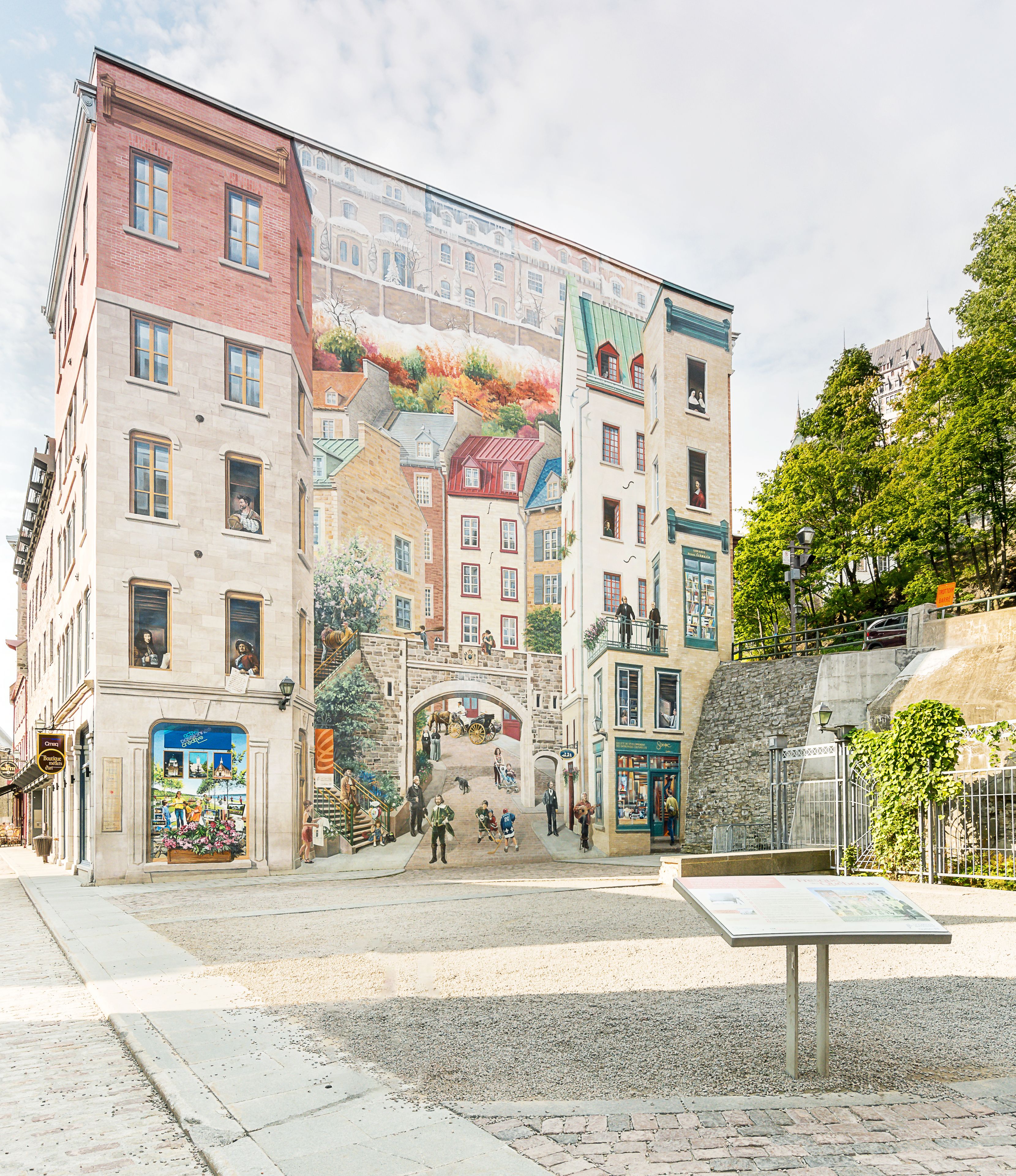 A historic building with a mural, a central plaza, and a stone fountain.