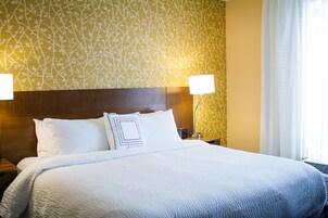 Una cama bien hecha con sábanas blancas y una pared estampada al fondo.