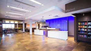 A spacious indoor area with a reception desk, a market section with snack shelves, and a seating area with tables and chairs. - Fairfield Inn and Suites Denver Northeast Brighton (Brighton)