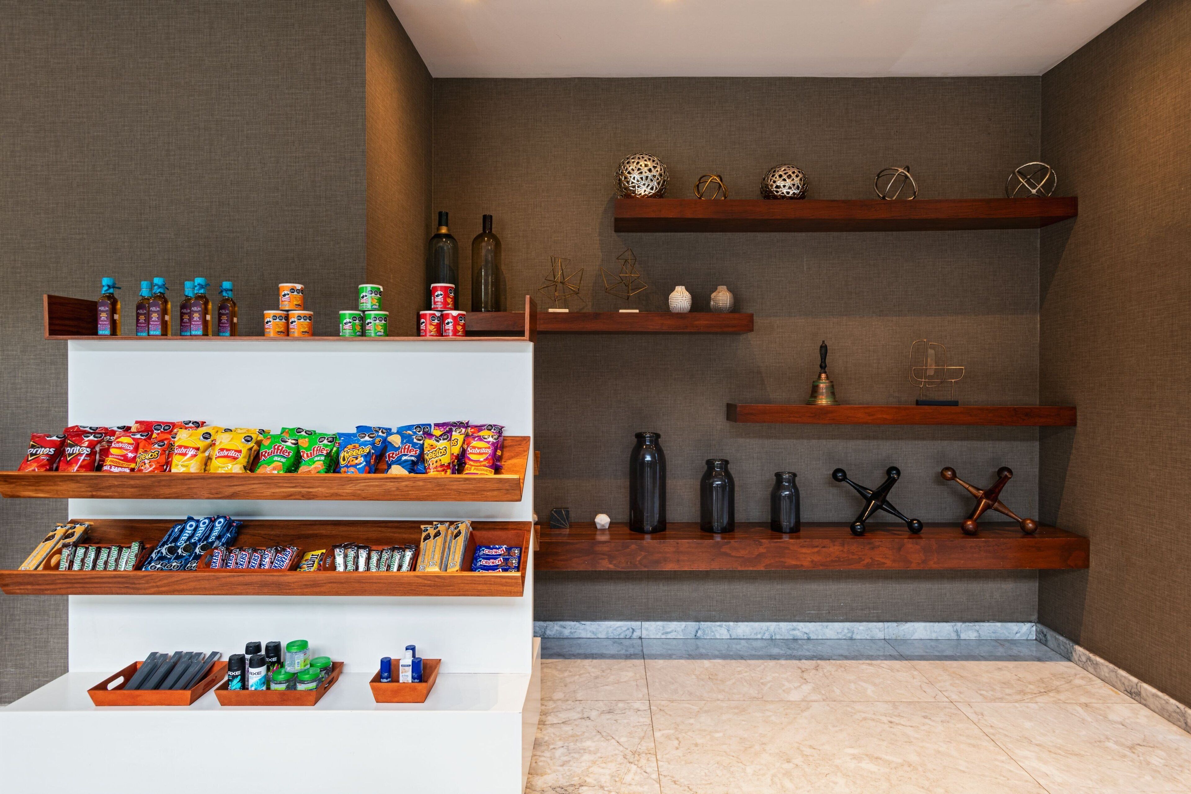Un vestíbulo de hotel con estantes de madera que exhiben aperitivos, bebidas y objetos decorativos.