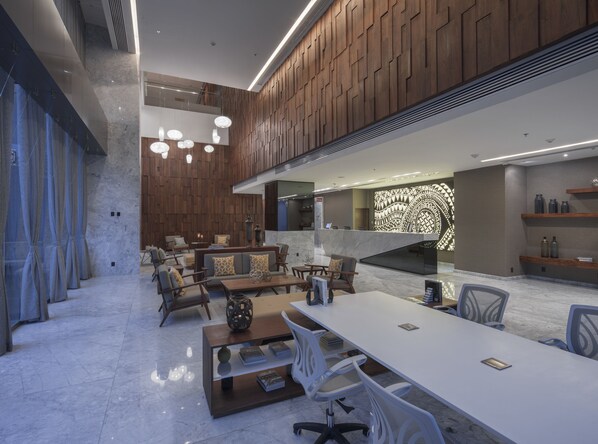 Un moderno vestíbulo de hotel con mostrador de recepción, zona de estar y una pared decorativa.