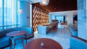 Un vestíbulo moderno con un área de estar curva, un bar central y un techo alto con paneles de madera.