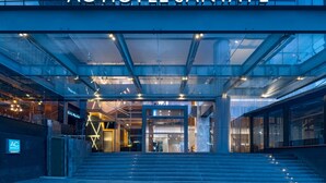 Exterior del AC Hotel Santa Fe con un diseño moderno, que presenta una fachada de vidrio y una entrada destacada con escalones que conducen a las puertas.