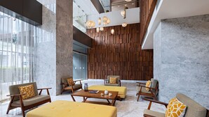 Un vestíbulo moderno con pared de madera, suelo de mármol y mobiliario amarillo.
