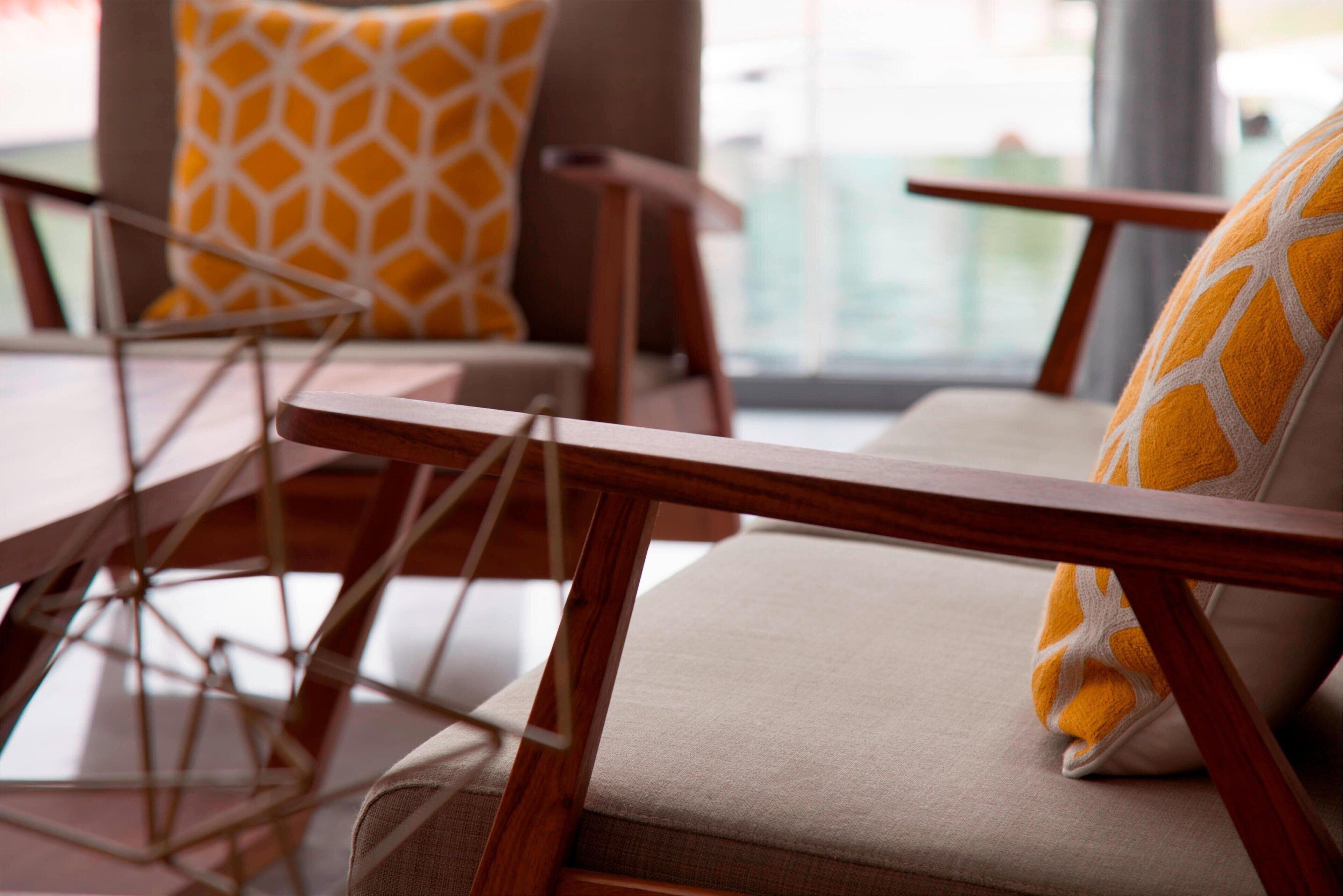 A modern lounge area with wooden furniture and patterned cushions.