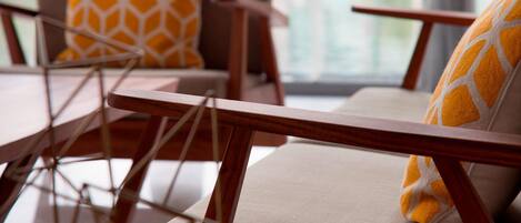 A modern lounge area with wooden furniture and patterned cushions.