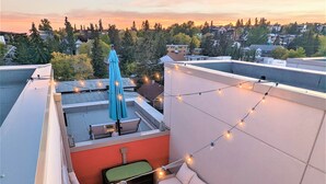 A rooftop terrace with a sofa, a small table, string lights, and a patterned rug. - Monki Di Executive Suites - GLAS - Luxury Inner City Home 3 min to Downtown w Private Rooftop Patio Fireplace (Calgary)