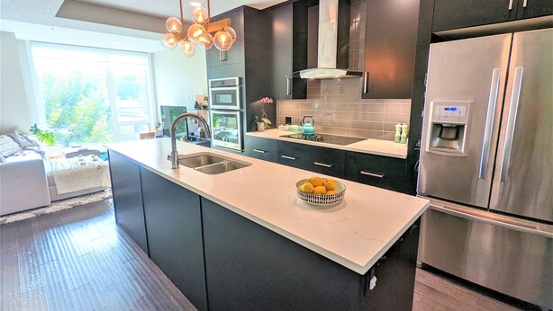 A modern kitchen with a central island, stainless steel appliances, and a large window providing natural light. - Monki Di Executive Suites - GLAS - Luxury Inner City Home 3 min to Downtown w Private Rooftop Patio Fireplace (Calgary)