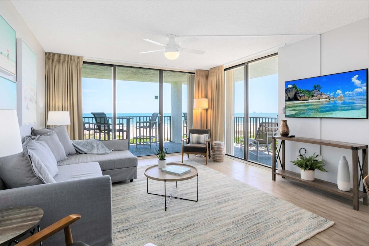 Een moderne hotelkamer met balkon, een bank, een salontafel en een televisie.