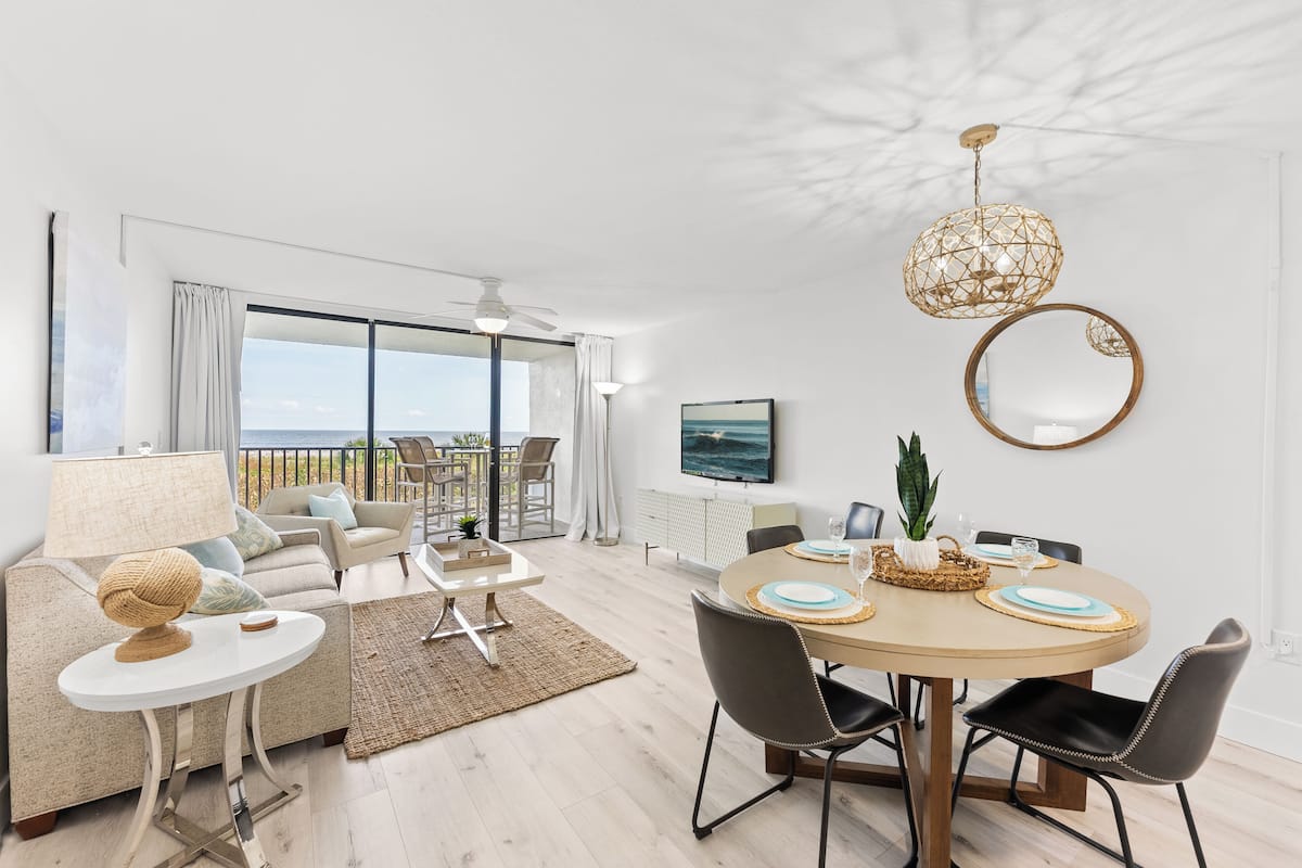 Een moderne woonkamer met een eethoek, grote ramen en een balkon.