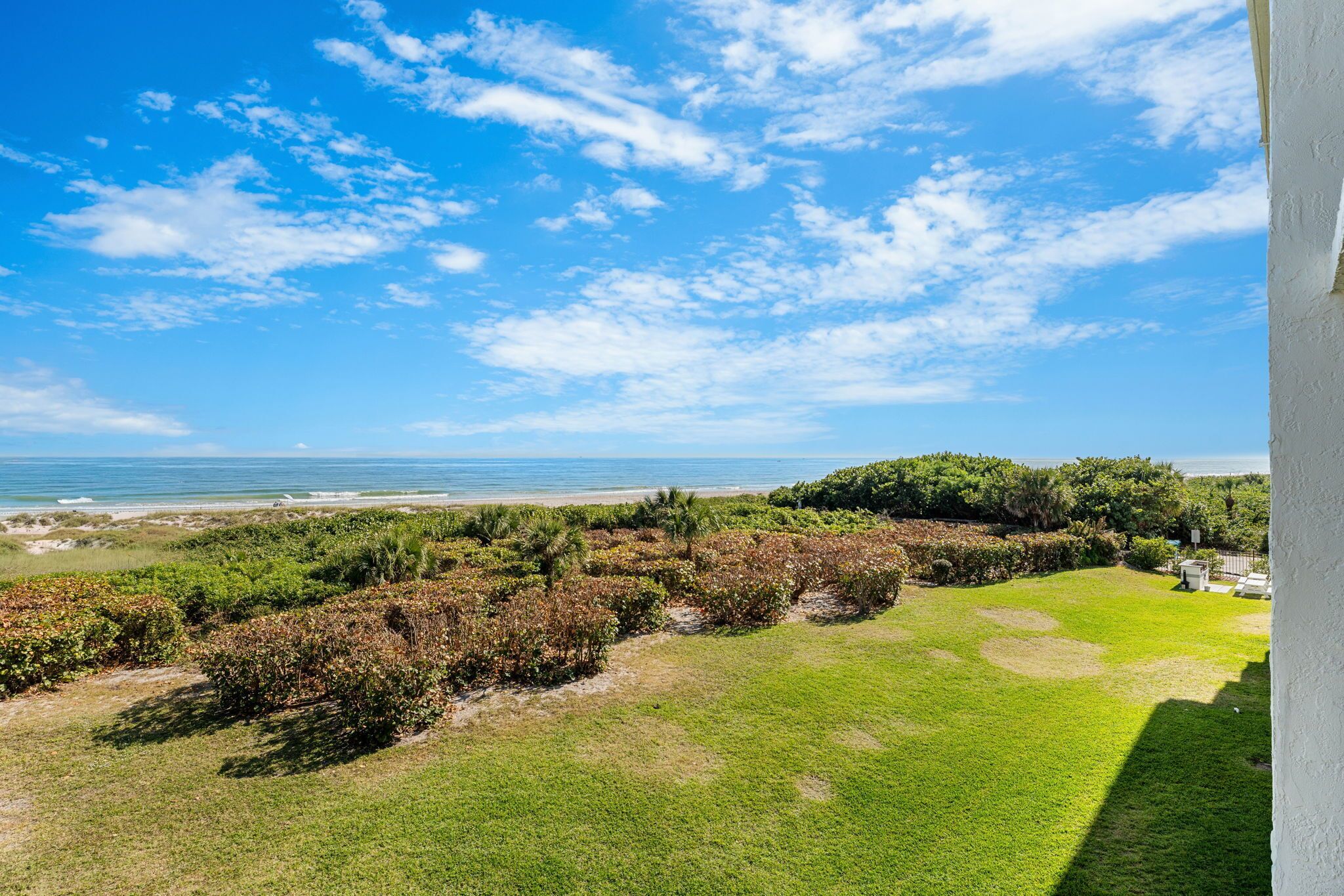 A coastal view with a grassy area, trees, and a clear sky.