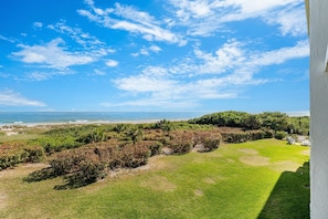 A coastal view with a grassy area, trees, and a clear sky. - Cape Winds - Oceanfront Pool, Tennis & Sauna Condos near Port Canaveral (Cape Canaveral)