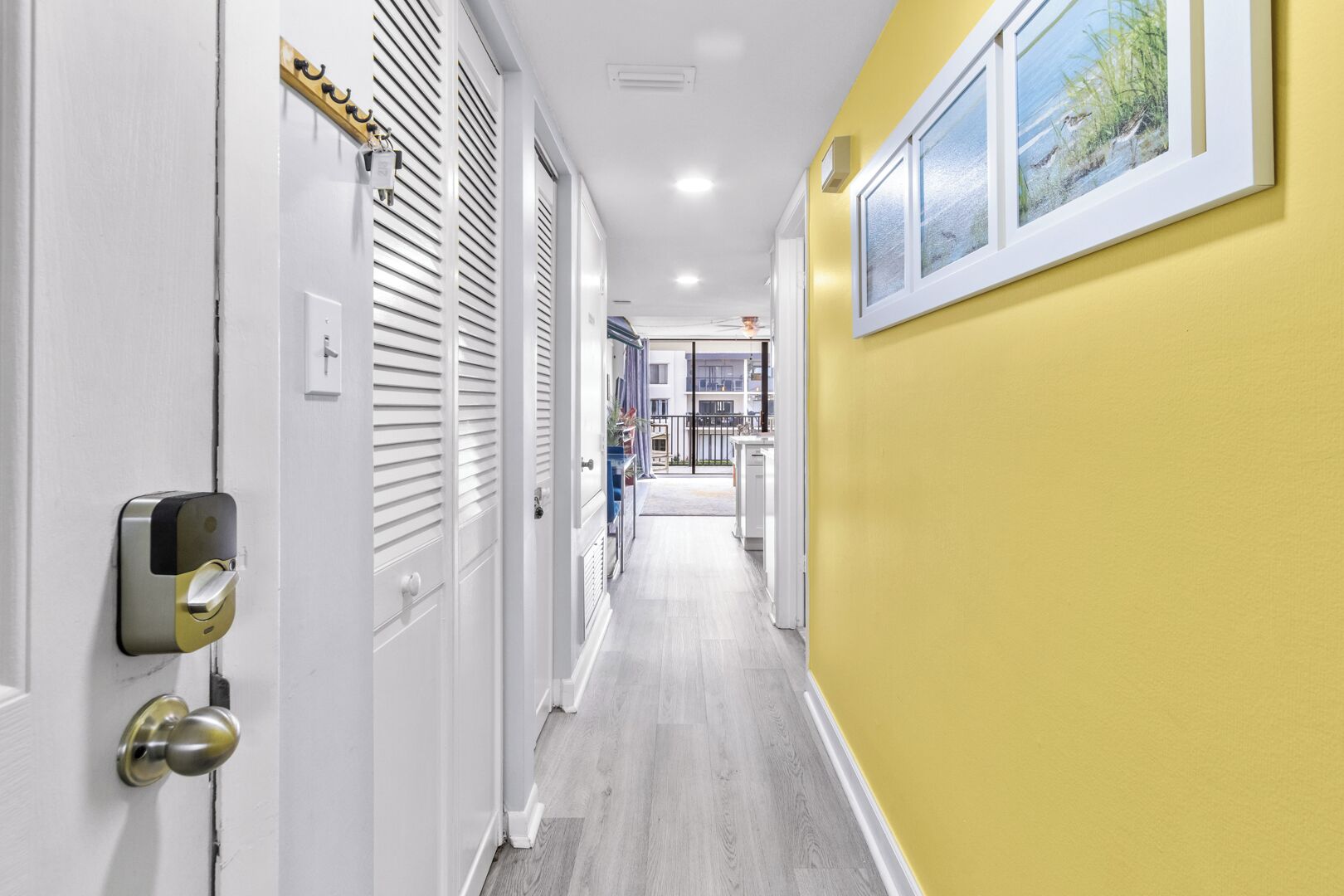 Un couloir avec une porte dotée d’une serrure moderne, une fenêtre donnant sur l’extérieur et un mur jaune.