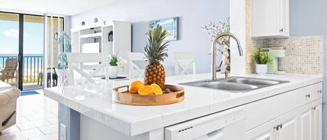 Una cocina moderna con una isla grande, armarios blancos y vistas al exterior.
