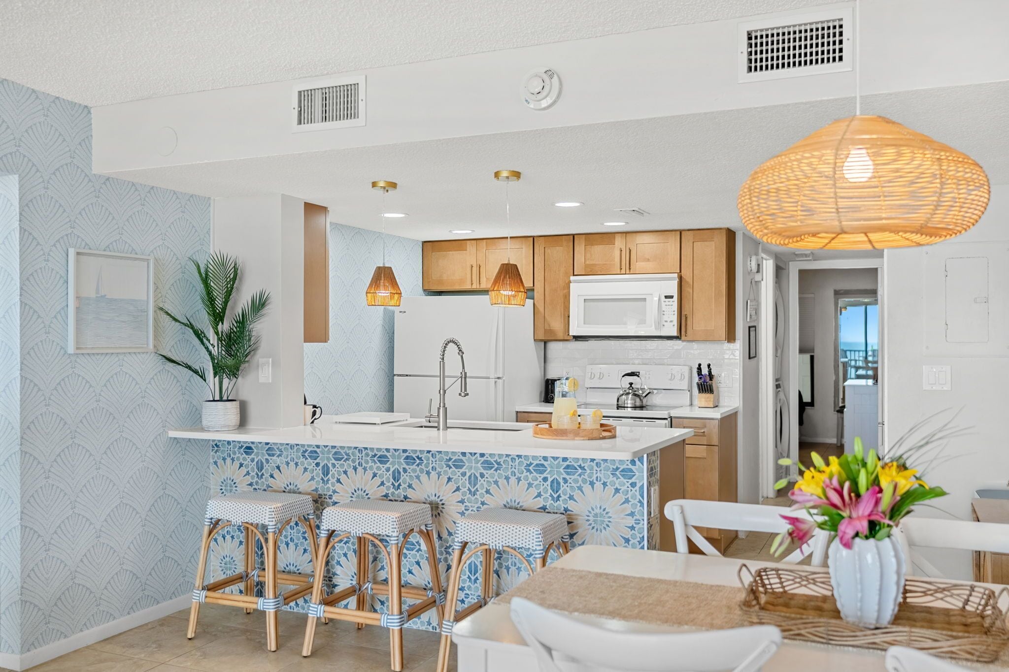 Una cocina moderna con una isla central, armarios blancos y una lámpara colgante.