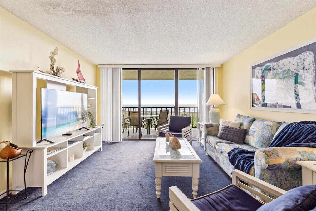 Een woonkamer met een televisie, bank, salontafel en een balkon met uitzicht.
