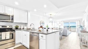 A modern kitchen with white cabinetry, stainless steel appliances, and a large island. - Spanish Main - Cocoa Beach Oceanfront Condos near Port Canaveral (Cocoa Beach)