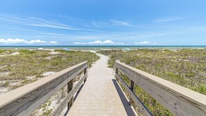 A wooden boardwalk leading to a beach with dunes and sparse vegetation. - Spanish Main - Cocoa Beach Oceanfront Condos near Port Canaveral (Cocoa Beach)