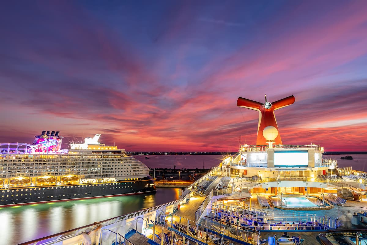 A cruise ship docked at a port with a large screen displaying "Carnival Cruise Line" and a prominent funnel structure.
