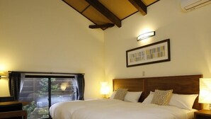 A bedroom with a large bed, wooden floor, a ceiling fan, and a window with curtains. - Longlife Resort Yufuin Bettei (Yufu)