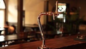 A bar area with a copper tap and a wooden counter. - Hakuba Pension Karunaju (Hakuba)
