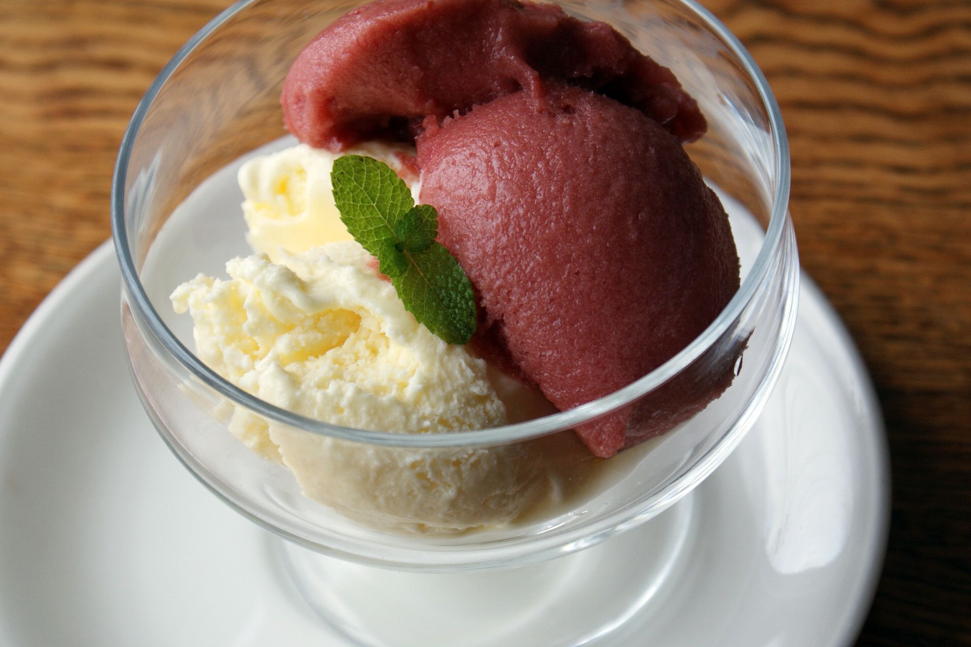 A dessert in a clear glass bowl on a white plate.