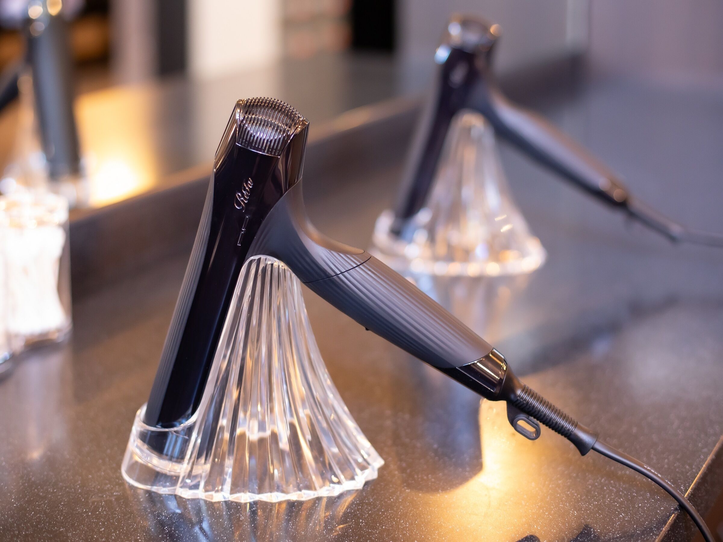 A close-up of a hair styling tool on a counter with a clear, reflective surface.