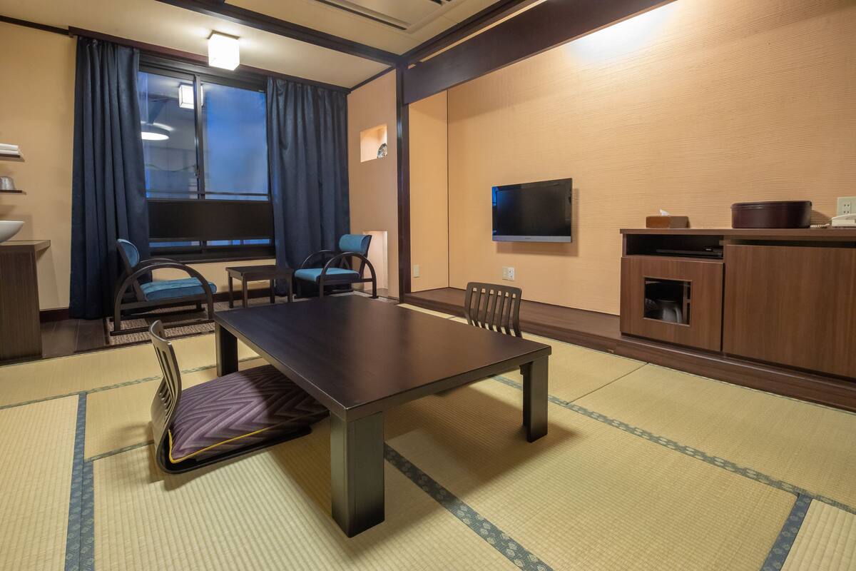 Une pièce de style japonais traditionnel, avec un sol recouvert de tatamis, une table basse et des sièges.