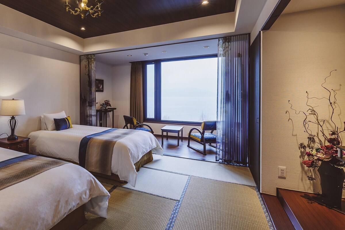 Une chambre d’hôtel avec deux lits, un bureau, une chaise et une vue sur la ville.