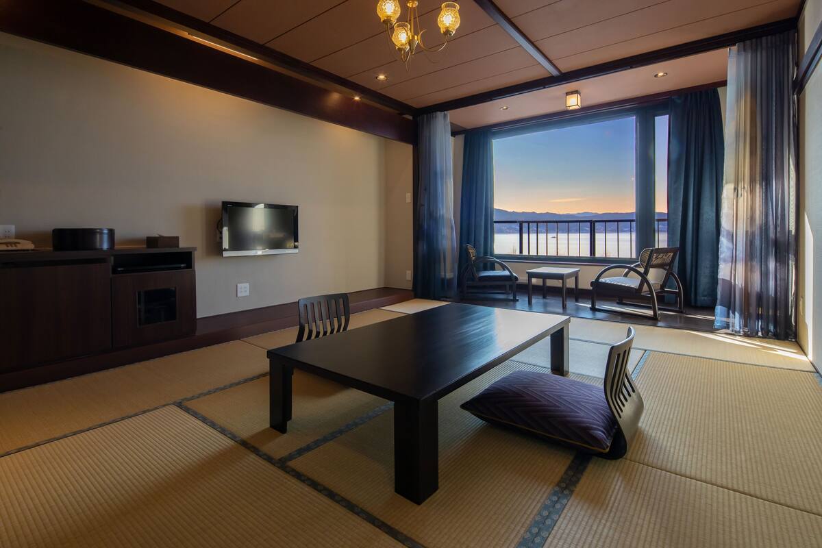 Une chambre d’hôtel dotée d’une grande table, de chaises, d’un téléviseur et offrant une vue sur la mer.