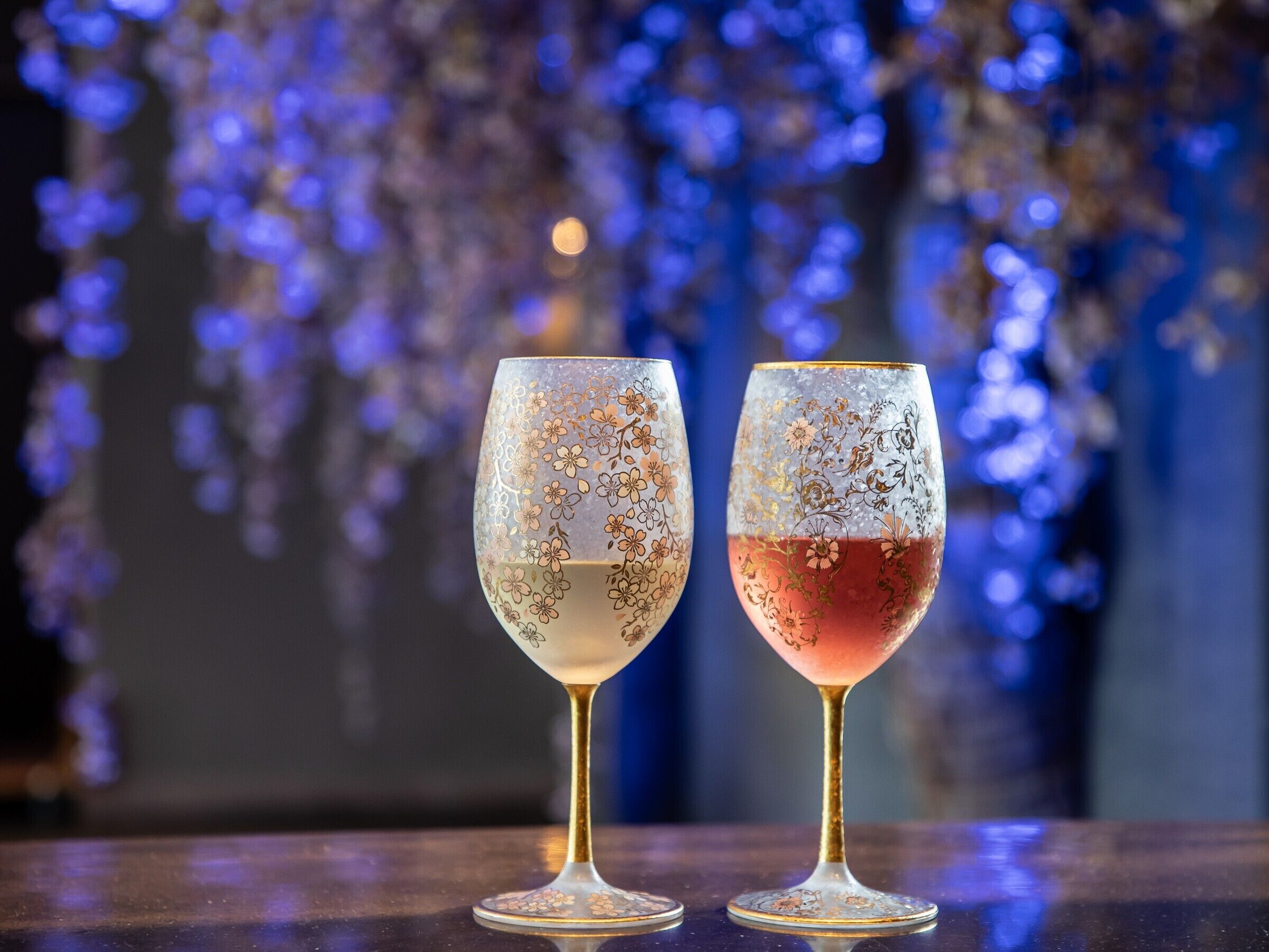 Two wine glasses with floral designs on a reflective surface.