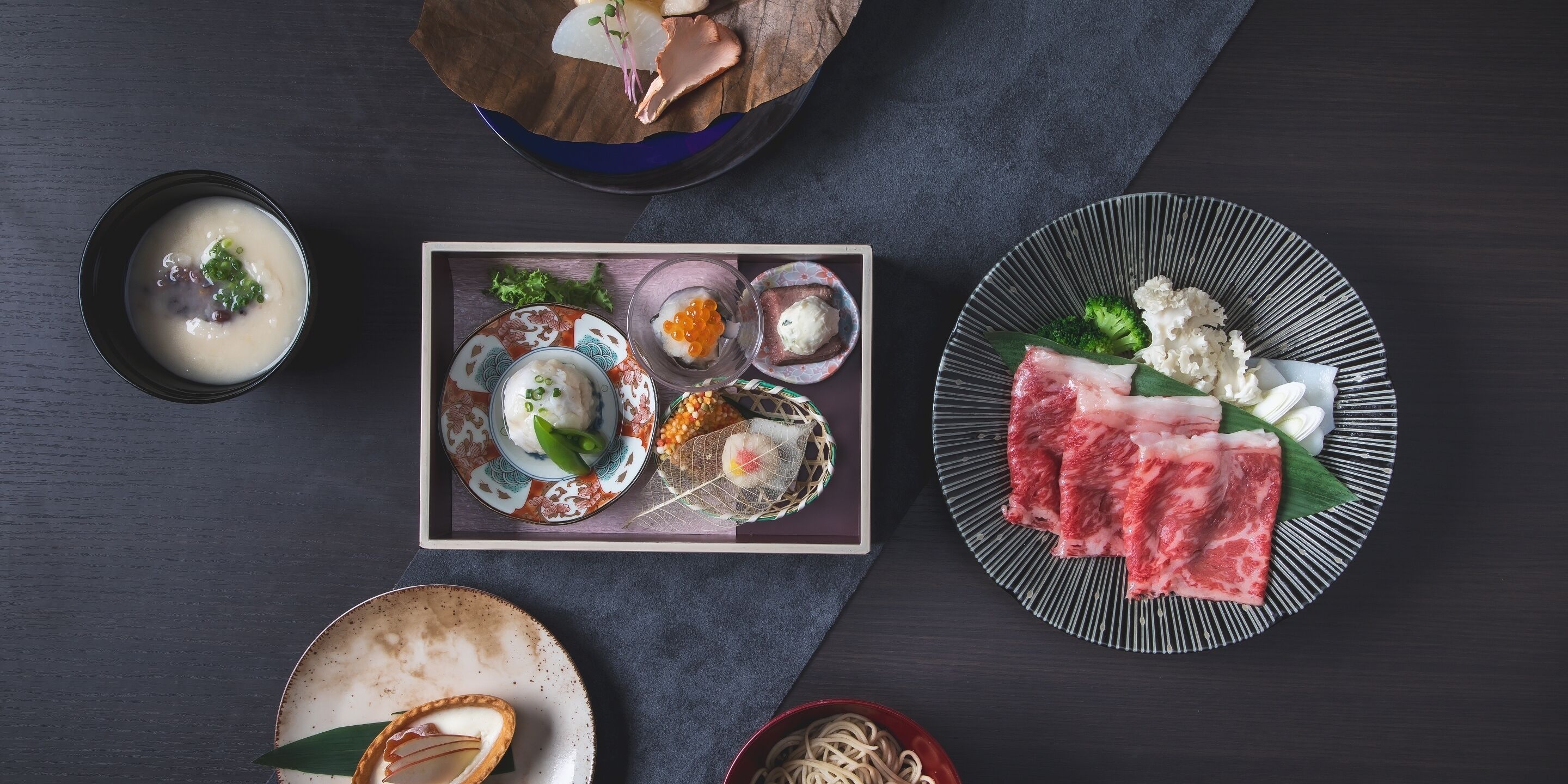 A variety of Japanese dishes including sushi, sashimi, and a bowl of soup.