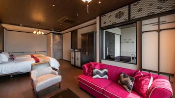 Een moderne hotelkamer met een bed, een rode bank, een fauteuil en een grote spiegel.