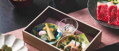 Una comida tradicional japonesa con varios platos, incluyendo sushi, sashimi y un tazón de sopa.