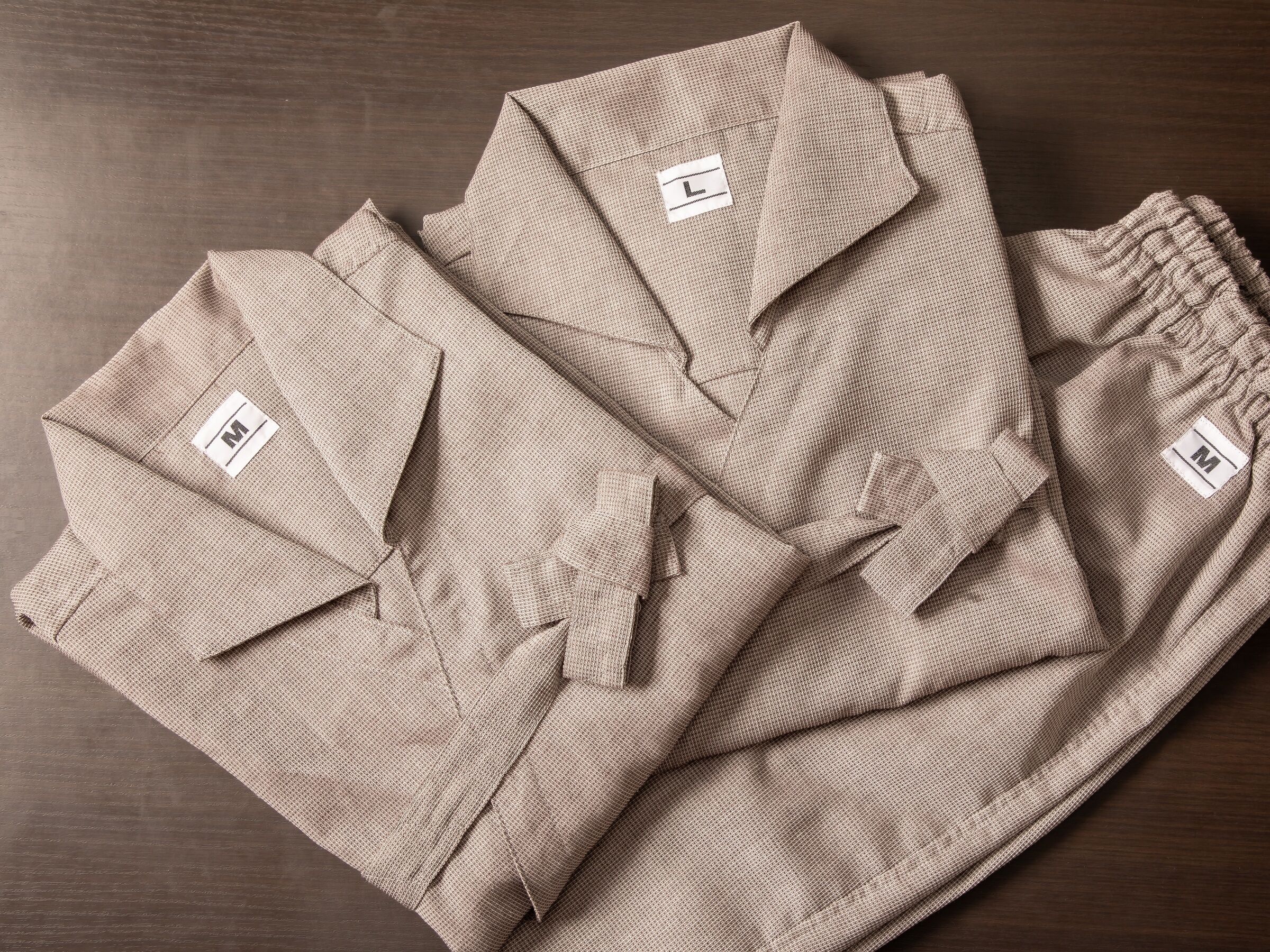 A neatly folded set of beige checkered shirts with visible size labels on the chest.