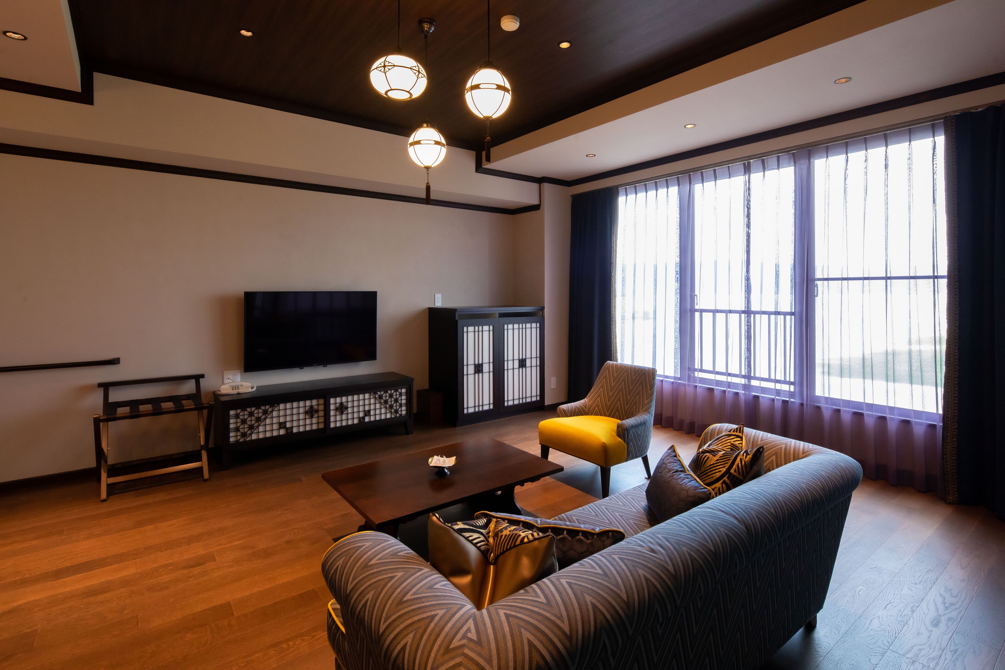 Een moderne woonkamer met een bank, fauteuil, salontafel, televisie en een kast.