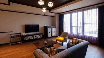 Een moderne woonkamer met een bank, fauteuil, salontafel, televisie en een kast.