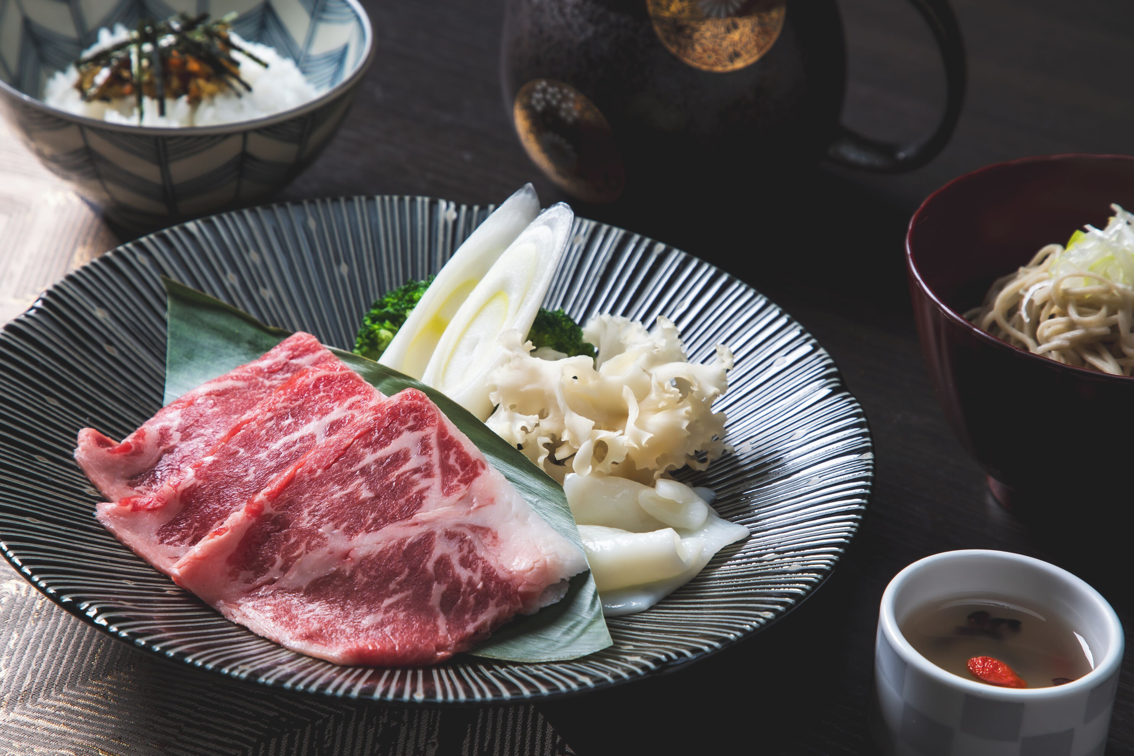 Ein Teller mit Fleisch, Gemüse und Nudeln auf einem Tisch.