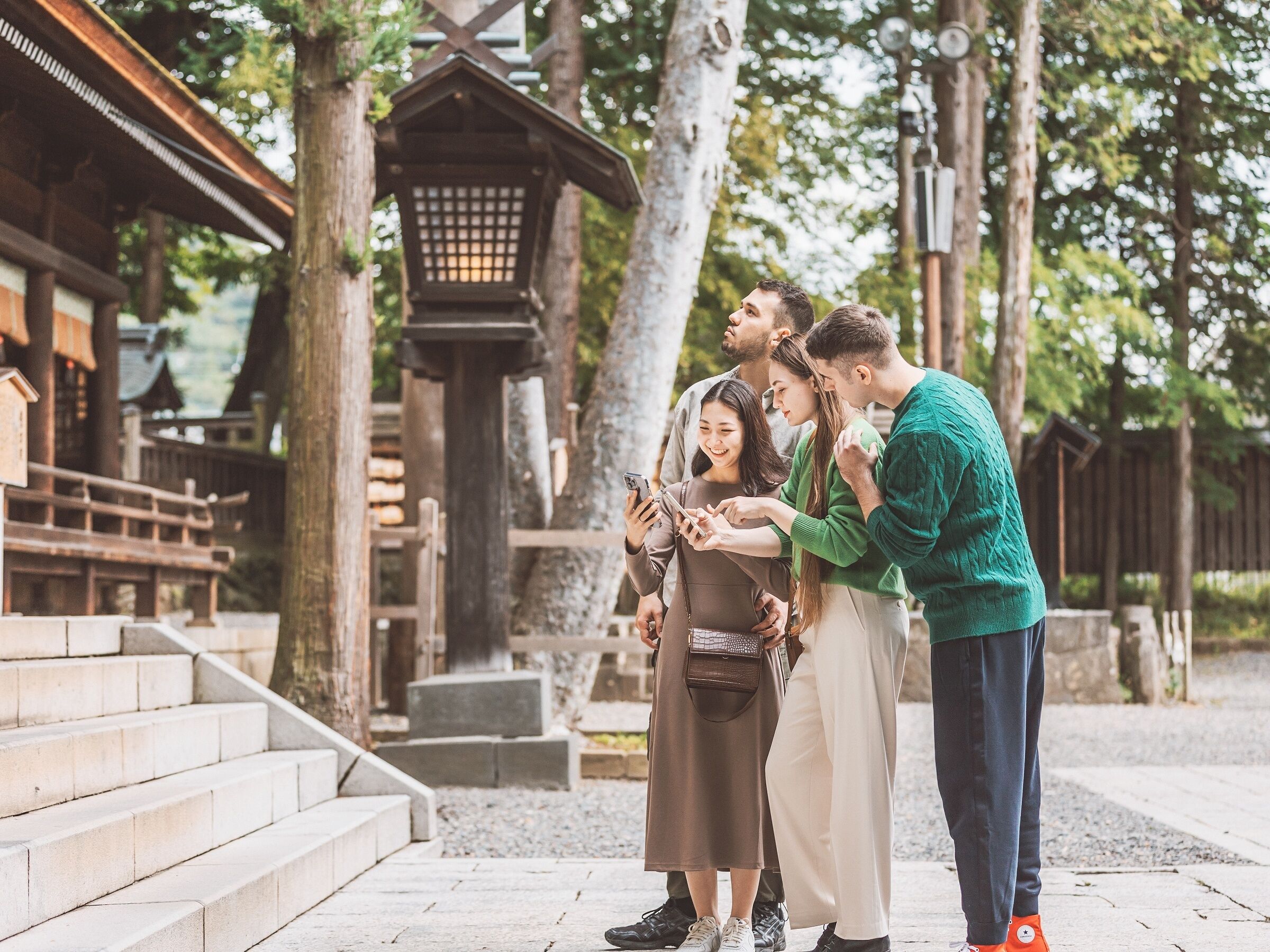 A group of people standing near a traditional wooden structure with steps leading up to it.