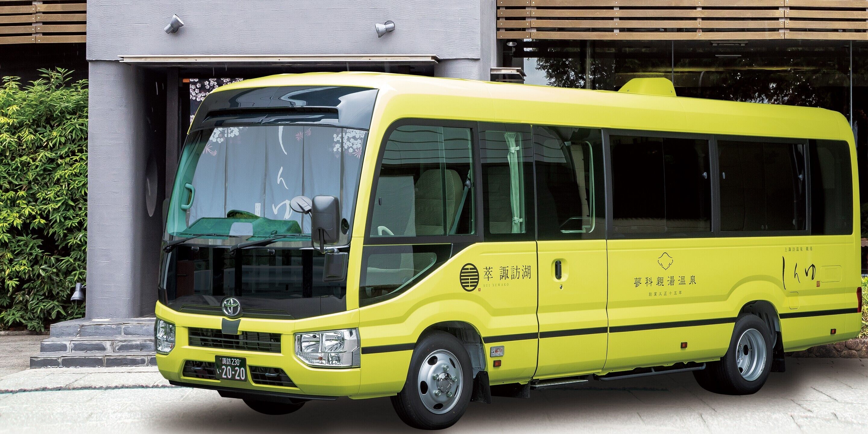 Un autobus jaune est garé devant un immeuble doté d’une grande fenêtre et d’une porte.