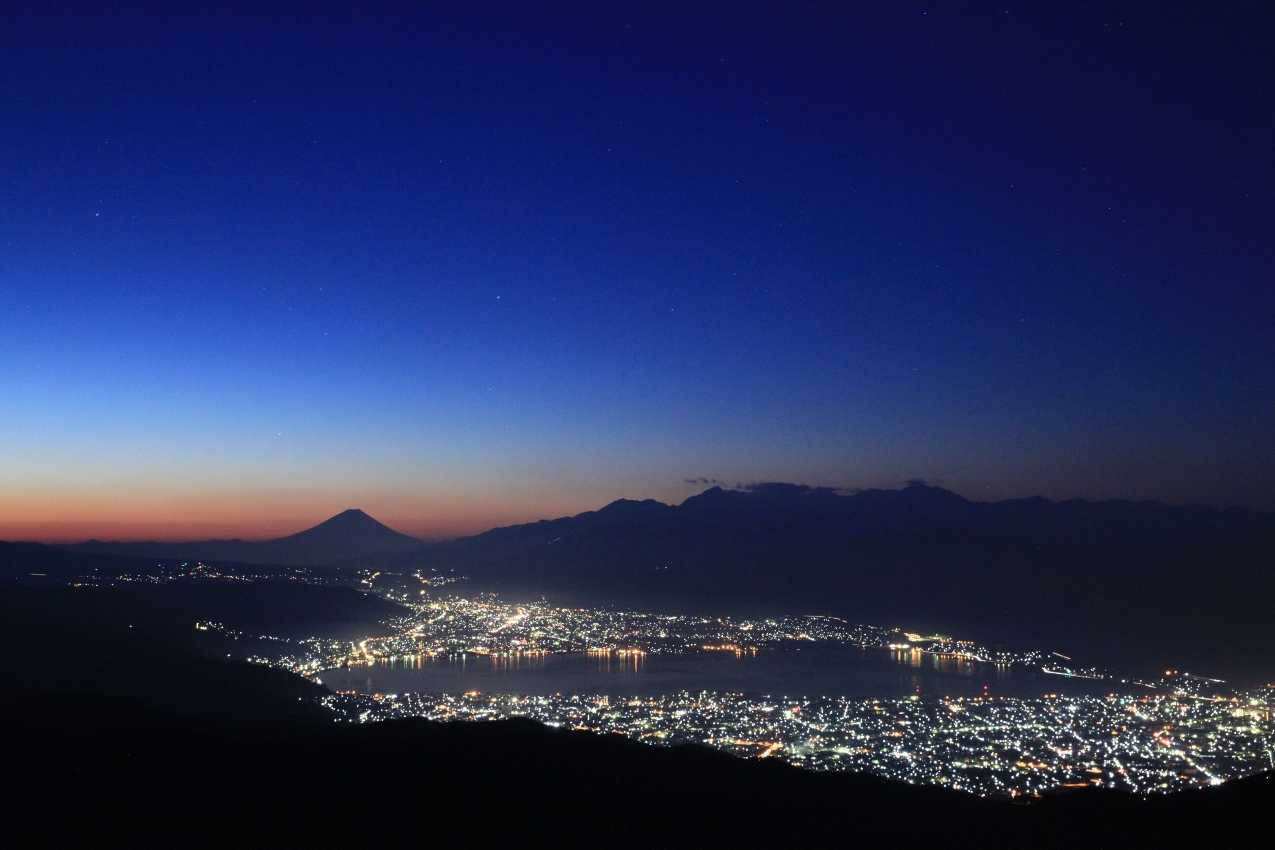 A nighttime cityscape with a mountain in the background.